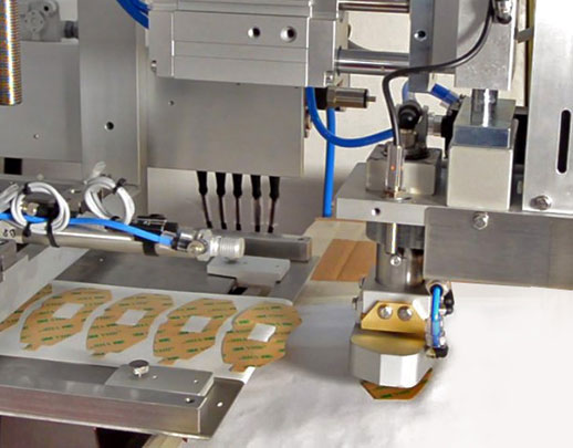 dettaglio del tampone che preleva un'etichetta per pastiglie freno auto ruotandola di 180° e applicandola su una superficie di test